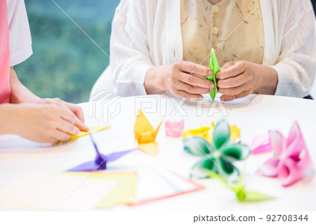 A senior woman folding origami and a caregiver Photography cooperation "LINK FOREST" 92708344