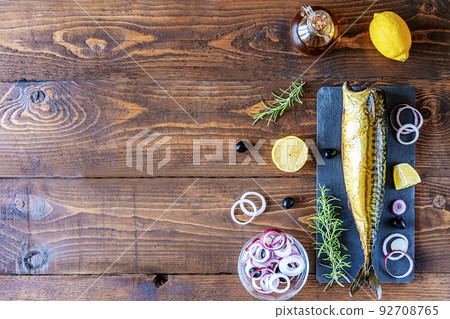 Smoked mackerel on stone cutting board, rings of onion, lemon, olives, olive oil, rosemary over wooden background Smoked mackerel on stone cutting board, rings of onion, lemon, olives, olive oil, rosemary over wooden background 92708765