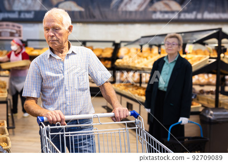 older man shopping buns and bread in bakery section of supermarket older man shopping buns and bread in bakery section of supermarket 92709089
