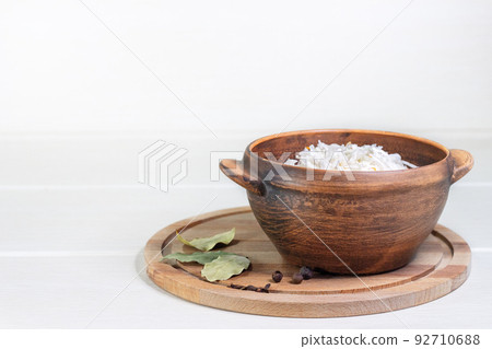 Homemade sauerkraut in a wooden bowl. Dish is decorated with a bay leaf and peppercorns. Homemade sauerkraut in a wooden bowl. Dish is decorated with a bay leaf and peppercorns. 92710688