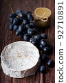 Wheel Camembert with black grapes and honey on wooden table. 92710891