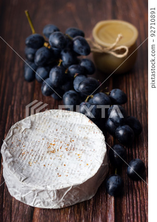 Wheel Camembert with black grapes and honey on wooden table. Wheel Camembert with black grapes and honey on wooden table. 92710891