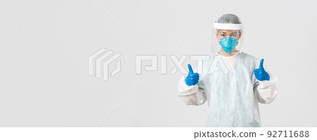 Covid-19, coronavirus disease, healthcare workers concept. Confident serious-looking asian female doctor working in contagious zones in personal protective equipment, show thumbs-up 92711688