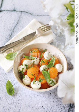 Summer light food. Mozzarella and melon salad with basil 92711805