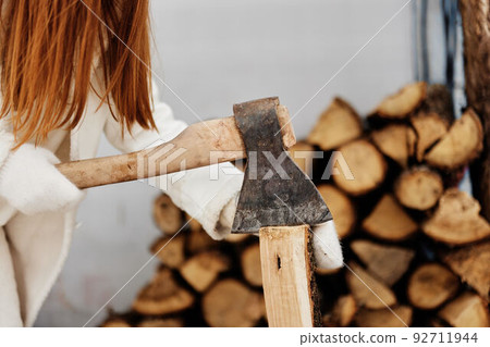 Happy young woman sitting next to firewood heating winter nature winter holidays Happy young woman sitting next to firewood heating winter nature winter holidays 92711944