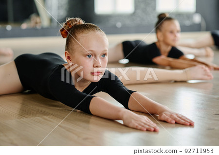 Flexible girl looking forwards while bending and stretching arms in twine pose 92711953