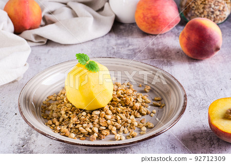 Frozen peach filled with yogurt on granola on a plate on the table. Korean trendy Greek momo 92712309