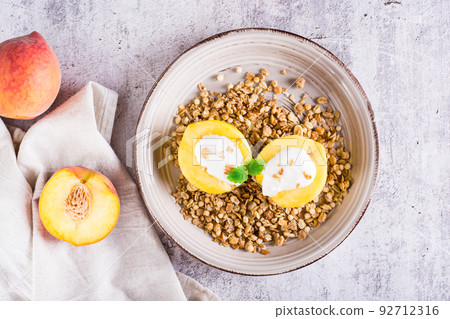 Peach halves filled with yogurt on granola on a plate. Korean trendy Greek momo. Top view Peach halves filled with yogurt on granola on a plate. Korean trendy Greek momo. Top view 92712316
