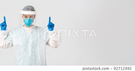 Covid-19, coronavirus disease, healthcare workers concept. Serious-looking young asian female doctor, tech lab employee in respirator and personal protective equipment, white background 92712892