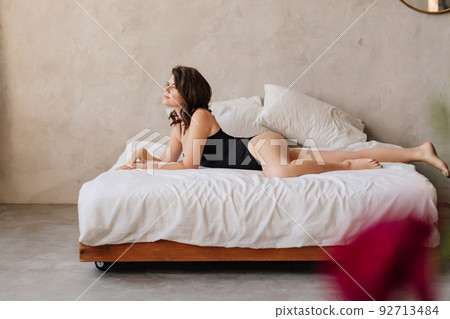 a sexy woman in a black bodysuit on the bed in the bedroom.  92713484