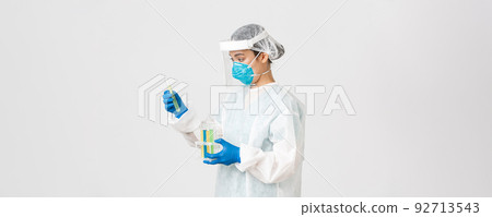 Covid-19, coronavirus disease, healthcare workers concept. Side view of careful serious asian female doctor, tech lab employee in personal protective equipment holding test-tube probes of vaccines 92713543