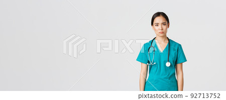 Covid-19, healthcare workers, pandemic concept. Exhausted young asian female nurse, doctor looking tired after shift in hospital, looking sad with fatigue, standing white background in scrubs 92713752