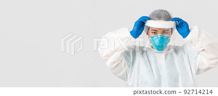Covid-19, coronavirus disease, healthcare workers concept. Confident serious-looking asian female doctor, put on face shield and personal protective equipment before entering contagious zone 92714214