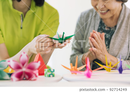 Caregiver and senior woman folding origami 92714249