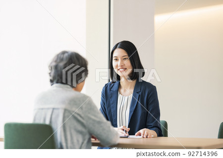 A woman explaining to a senior woman 92714396