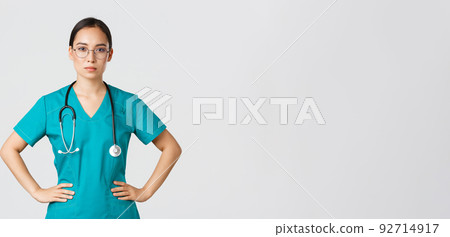 Covid-19, healthcare workers, pandemic concept. Confident determined asian female nurse helping patients, working with coronavirus disease, looking ready, wearing scrubs and glasses, white background 92714917