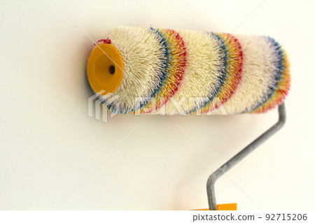 Paint roller brush near wall in renovated room interior isolated on white background. Renovation and DIY concept. Paint roller brush near wall in renovated room interior isolated on white background. Renovation and DIY concept. 92715206