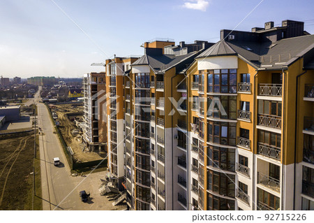 New tall apartment buildings and parked cars and suburb houses on blue sky copy space background. New tall apartment buildings and parked cars and suburb houses on blue sky copy space background. 92715226