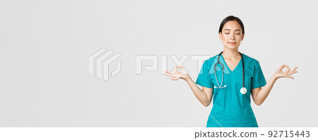 Covid-19, healthcare workers and preventing virus concept. Calm and patient asian female doctor, nurse in scrubs staying relaxed, meditating with eyes closed and happy smile, white background 92715443