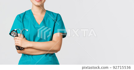 Covid-19, coronavirus disease, healthcare workers concept. Cropped shot of asian female doctor body smiling, cross arms chest confident and holding stethoscope, standing white background Covid-19, coronavirus disease, healthcare workers concept. Cropped shot of asian female doctor body smiling, cross arms chest confident and holding stethoscope, standing white background 92715536