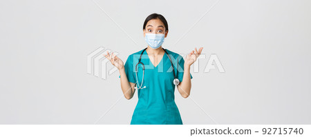 Covid-19, coronavirus disease, healthcare workers concept. Surprised and amazed asian female nurse, physician in medical mask and scrubs raising hands up excited, hear amazing news, white background Covid-19, coronavirus disease, healthcare workers concept. Surprised and amazed asian female nurse, physician in medical mask and scrubs raising hands up excited, hear amazing news, white background 92715740