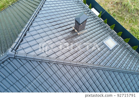 Closeup of house roof top covered with shiny ceramic shingles. Closeup of house roof top covered with shiny ceramic shingles. 92715791
