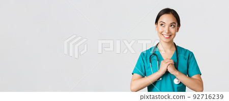 Healthcare workers, preventing virus, quarantine campaign concept. Determined and confident asian female physician in scrubs, clench hands together, getting ready, looking upper left corner Healthcare workers, preventing virus, quarantine campaign concept. Determined and confident asian female physician in scrubs, clench hands together, getting ready, looking upper left corner 92716239