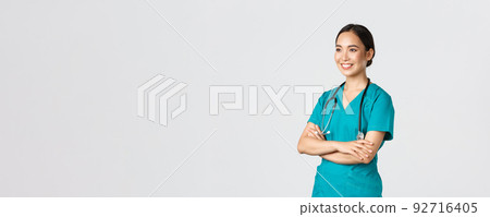 Covid-19, healthcare workers, pandemic concept. Side view of professional confident and hopeful asian female doctor, nurse looking assured away and smiling, standing in scrubs white background 92716405