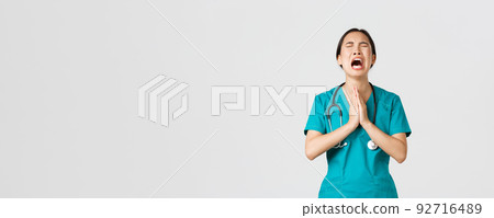 Covid-19, healthcare workers, pandemic concept. Overworked sad and tired asian female doctor, nurse begging for help, pleading god and crying from stress, standing white background 92716489