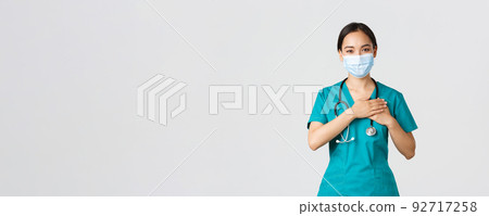Covid-19, coronavirus disease, healthcare workers concept. Friendly caring asian female doctor, physician in medical mask and gloves, holding hands on heart and smiling, white background Covid-19, coronavirus disease, healthcare workers concept. Friendly caring asian female doctor, physician in medical mask and gloves, holding hands on heart and smiling, white background 92717258