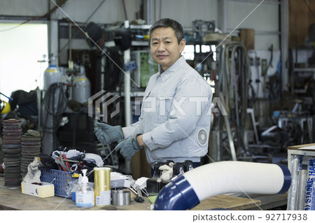 Male worker preparing with welding gloves in the factory Male worker preparing with welding gloves in the factory 92717938