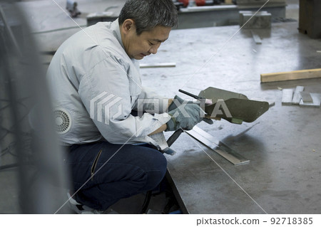 Image of a welder A middle-aged male worker wearing air-conditioned work clothes and preparing for welding Image of a welder A middle-aged male worker wearing air-conditioned work clothes and preparing for welding 92718385