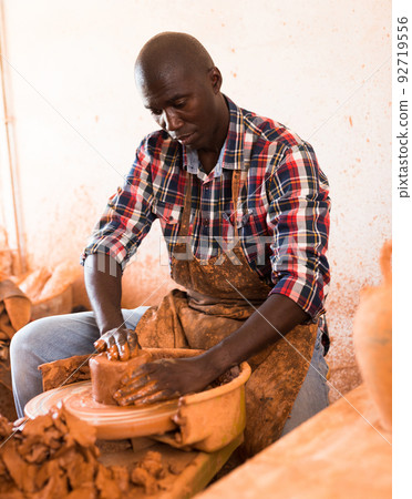 Man focused on work on pottery wheel 92719556