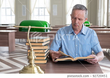 Portrait of caucasian Senior man working with book in public library. Adult student at the library Portrait of caucasian Senior man working with book in public library. Adult student at the library 92720451
