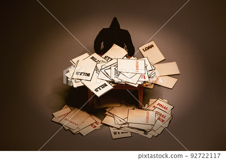 Man looking at piles of warning notices and over due letters on a table in dark background. Debt and bankruptcy concept. Man looking at piles of warning notices and over due letters on a table in dark background. Debt and bankruptcy concept. 92722117