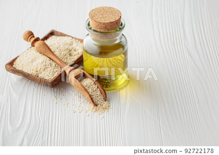 Sesame seeds and oil on an white wooden table. Sesame seeds and oil on an white wooden table. 92722178