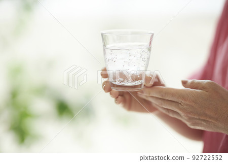 Middle woman's hand holding a glass of water Middle woman's hand holding a glass of water 92722552