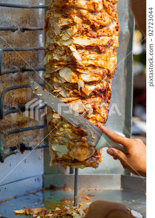 Chef cutting with doner knife Traditional Turkish Doner Kebab meat. Chef cutting with doner knife Traditional Turkish Doner Kebab meat. 92723044