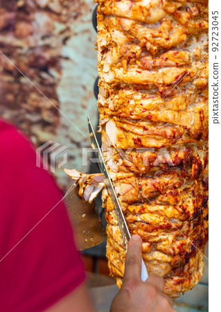 Chef cutting with doner knife Traditional Turkish Doner Kebab meat. Chef cutting with doner knife Traditional Turkish Doner Kebab meat. 92723045