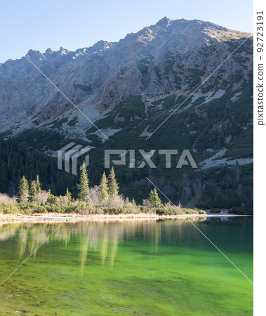 Vertical landscape shot of a green tarn below rocky mountain range, Europe, Slovakia 92723191