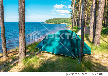 Tourist tent on a high bank of the lake, beautiful landscape summer sunny day Tourist tent on a high bank of the lake, beautiful landscape summer sunny day 92723816