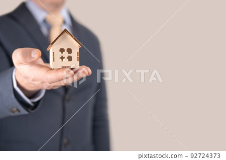 Business man in suit having miniature house on palm of his hand - Business mortgage, property loan, house insurance, business investment concept 92724373