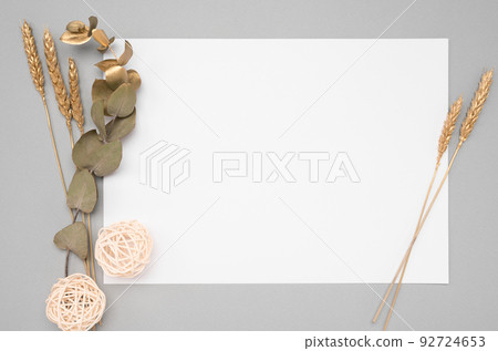 White invitation card mockup with a dried eucalyptus and golden ears decoration on a neutral table. 5x7 ratio, similar to A6, A5 92724653