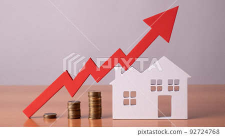 Coins on a table, a red up arrow and house. The concept of the rising price of real estate 92724768