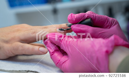 A man on a manicure procedure paints his nails black in a beauty salon 92725586