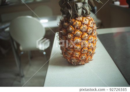 Whole pineapple fruit standing on the kitchen counter Whole pineapple fruit standing on the kitchen counter 92726385