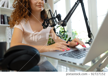 Woman vlogger looking at laptop and recording video with microphone Woman vlogger looking at laptop and recording video with microphone 92727152