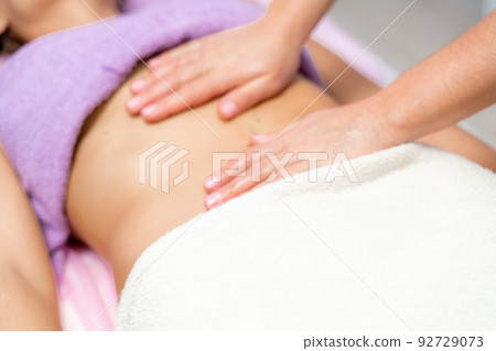 Top view of hands massaging female abdomen.Therapist applying pressure on belly. Woman receiving massage at spa salon 92729073