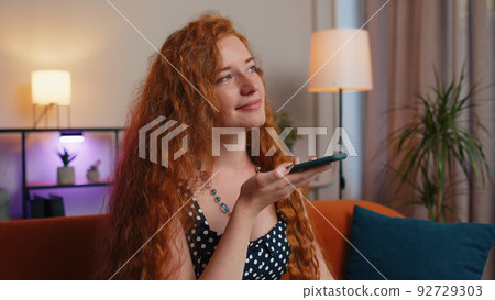 Red hair woman enjoying smartphone call talking, mobile phone conversation with friends at home Red hair woman enjoying smartphone call talking, mobile phone conversation with friends at home 92729303