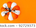 Halloween. White and orange striped pumpkin and black spiders. Place for text. Copy space. Flay lay. Top view. Layout for design. Orange background. Preparation for the Halloween holiday. 92729373